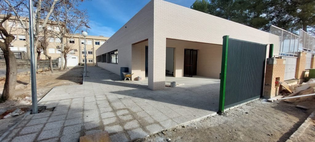 Edificación de una estructura moderna de una sola planta, con fachada de ladrillo claro y zona exterior en construcción.