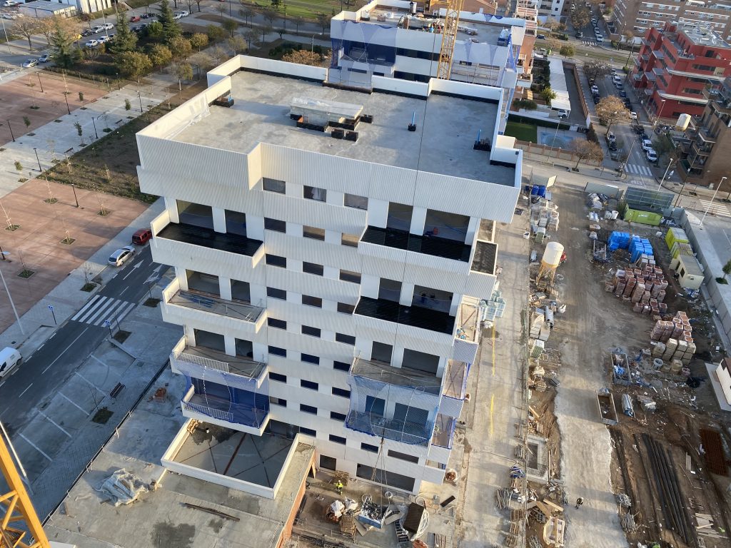 Edificio en proceso de construcción con varias plantas, andamios y trabajos de obra en ejecución.