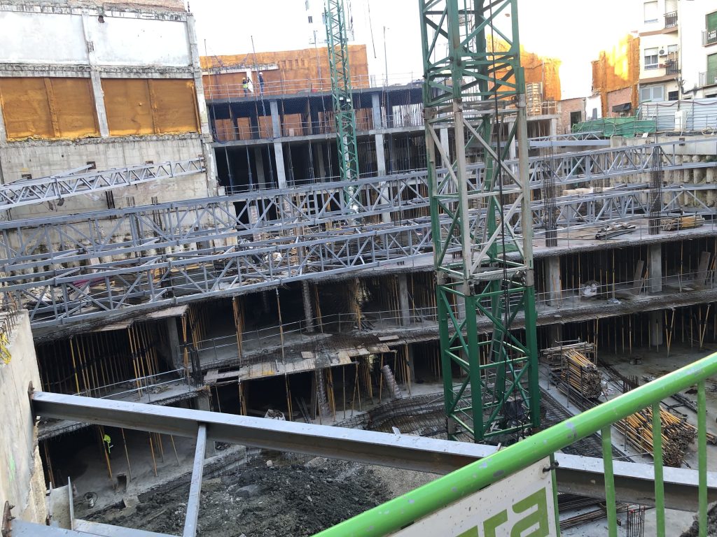 Estructura subterránea en fase de construcción con sistemas de apuntalamiento metálico y grúa torre.