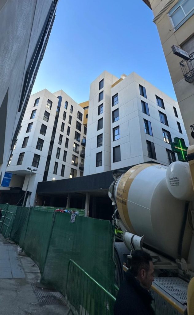 Edificio residencial moderno en fase de construcción, con estructura terminada y trabajos exteriores en curso.